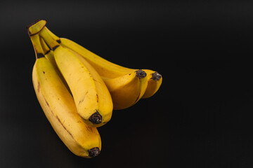Fresh yellow bananas arranged neatly on a dark surface