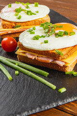 Breakfast sandwich with fried eggs and fresh ingredients on a slate board
