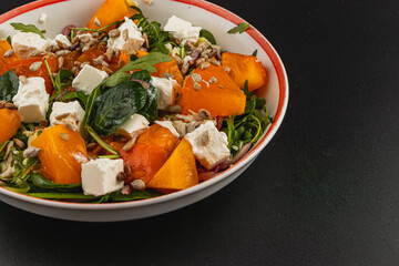 Fresh salad bowl with persimmons, feta cheese, and sunflower seeds