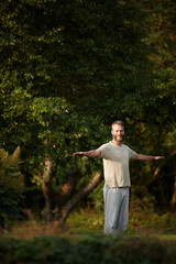 Portrait, man and stretching for yoga on grass with mindfulness, spiritual healing and peace at...