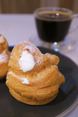 Closeup of a Delectable French Cream Puff with a Cup of Black Coffee
