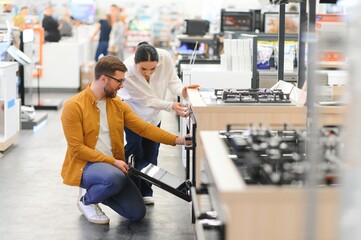 Young man and woman buying new gas stove in appliances shop