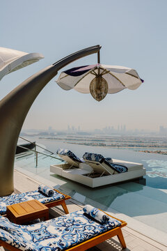 Luxurious infinity pool with elegant lounge chairs and parasols overlooking the stunning Dubai skyline and Atlantis The Palm. A serene escape blending modern architecture and breathtaking views