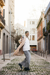 Young stylish woman with a reusable coffee cup dancing and having fun on the street