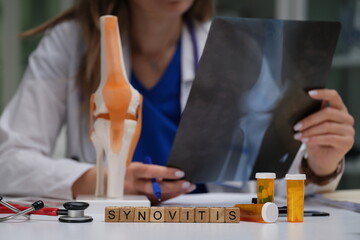A healthcare professional evaluates a knee model and Xrays to accurately diagnose synovitis during evaluation