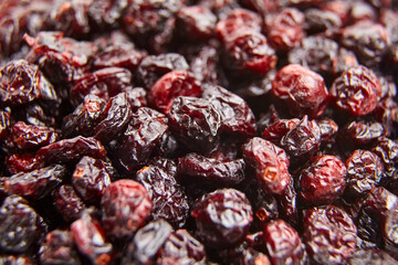 High-resolution close-up of dried cranberries with glossy textures, rich red tones, and wrinkled...