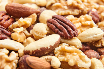 A detailed close-up of assorted mixed nuts, including pecans, walnuts, almonds, Brazil nuts, and cashews, showcasing their textures and colors