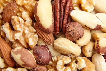 A close-up view of assorted mixed nuts, including walnuts, Brazil nuts, pecans, hazelnuts, almonds, and cashews, highlighting natural textures and variety