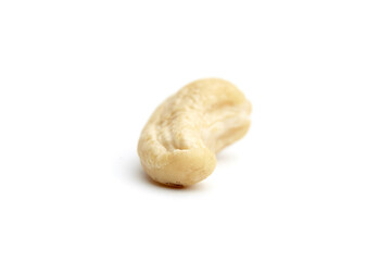 Close-up of a single raw cashew nut placed on a clean white surface. Perfect for healthy eating, plant-based diets, or natural food concepts