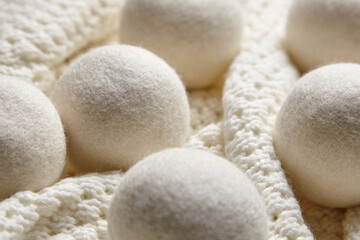 Close-up of white wool dryer balls on a textured, knitted blanket, creating a warm and cozy feel. Perfect for illustrating eco-friendly and sustainable laundry care
