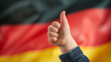 Bundestagswahl 2025 in Deutschland - Hand von einem Kind, dass seinen Daumen nach oben streckt, Deutschlandflagge im Hintergrund