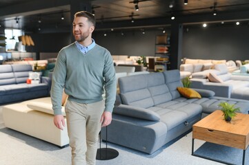 Young man buying sofa in furniture store