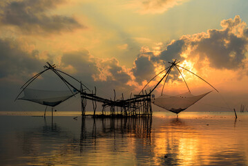Golden Hour Serenity: Traditional Thai fishing nets silhouetted against a vibrant sunset sky. Perfect for your next travel or nature-themed project.