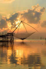 Golden Hour Serenity: Traditional Thai fishing nets silhouetted against a vibrant sunset sky. Perfect for your next travel or nature-themed project.