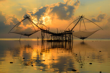 Golden Hour Serenity: Traditional Thai fishing nets silhouetted against a vibrant sunset sky. Perfect for your next travel or nature-themed project.