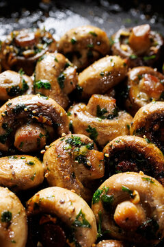 Saut&eacute;ed garlic butter mushrooms with parsley and black pepper, focus on mushroom in the middle, close-up view