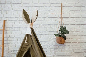Cozy indoor teepee with plant decor against white brick wall