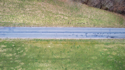 Aerial view shows a serene rural road winding through vibrant green landscapes, creating a peaceful scene
