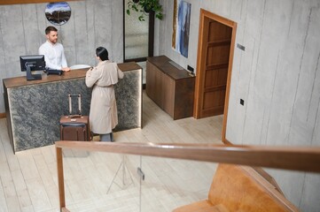 Female guests come with bags and suitcases to the hotel reception in the lobby