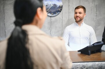 Portrait of a young male receptionist in a hotel lobby wearing a white shirt