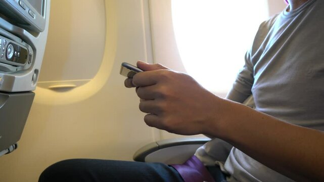 A man is using his cell phone while sitting in a chair. Concept of relaxation and leisure, as the man is focused on his phone rather than his surroundings