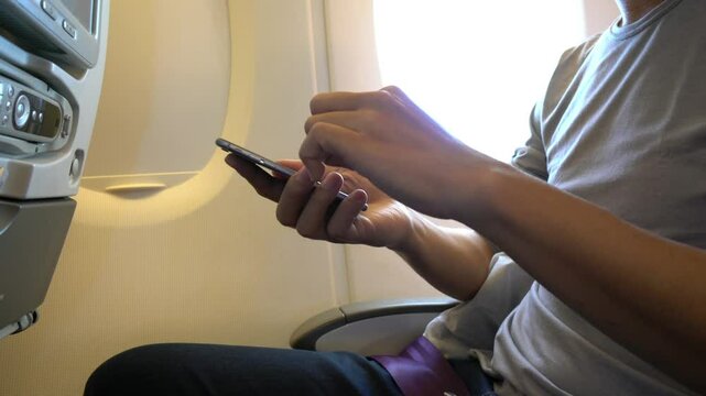 A man is using his cell phone while sitting in a chair. Concept of relaxation and leisure, as the man is focused on his phone rather than his surroundings