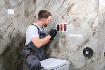 Plumber installing toilet in restroom
