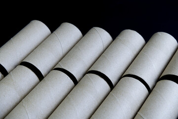 Cylinder of tissue paper core on black background. Close-up brown paper roll with copy space. Empty, eco-friendly, recycled, paper material, toilet concept for background. Stack of paper roll on black
