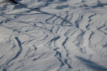 dettagli della superficie di un terreno naturale coperto dalla neve con forme variabili disegnate...