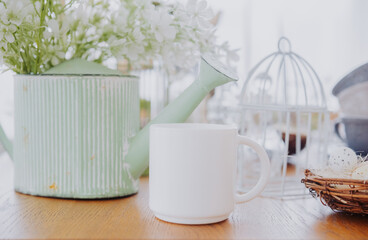 White mug with flowers and decorative items on a wooden table