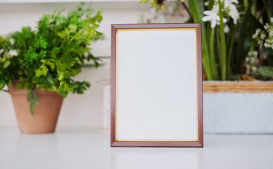 Blank wooden frame placed on a table near indoor plants in a modern space