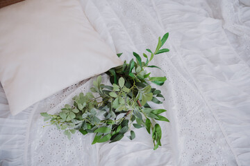 Soft white bedding with decorative greenery and pillow arranged artistically