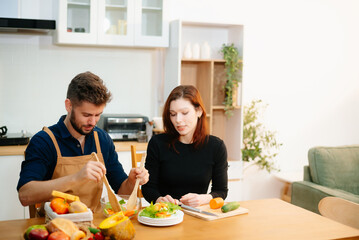 Discover a joyful couple preparing fresh vegetables, embracing healthy eating and teamwork in a vibrant kitchen