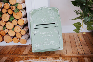 Vintage green post box positioned against stacked wooden logs indoors