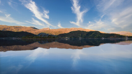 Fjord with view of mountains and fjord landscape in Norway. Blue sky, white clouds