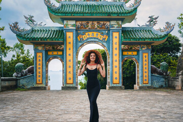 Woman traveler with Vietnamese hat and with a fan on the background at Linh Ung Pagoda temple...