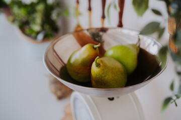 Fresh green pears on a vintage scale in a bright kitchen setting