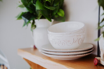 Elegant white dishware displayed on a wooden shelf in a cozy setting
