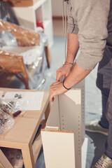 Man working and assembling furniture in a new apartment.