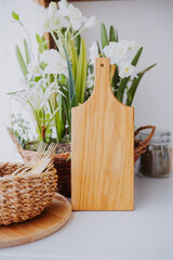Wooden cutting board with decorative plants and utensils on a kitchen countertop