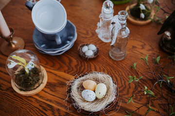 Nest of decorative eggs surrounded by elegant tableware in a cozy setting