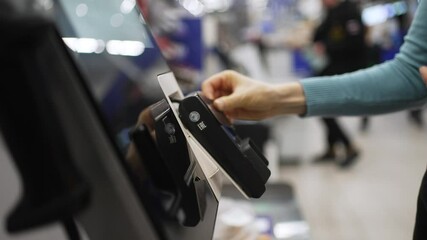 Female shopper performing contactless payment using credit card at self-service kiosk, showcasing modern, efficient retail technology and cashless transaction method - Powered by Adobe