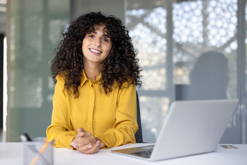 Successful woman at workplace inside office. Businesswoman smiling happily and looking at camera,...