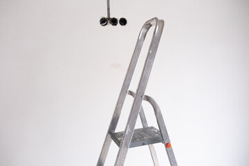 Metal ladder positioned under ceiling fixtures during home renovation work