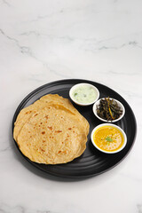 Roti and Sabzi. Indian vegetarian Thali includes bhindi fry, yellow daal tadka, cucumber raita, and chapati or tel paratha. Indian food is served in a plate or thali. Copy Space. healthy Veg Thali