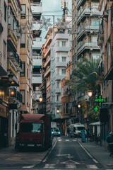Obraz premium Narrow Urban Street with Tall Buildings and Evening Atmosphere in Alicante Spain