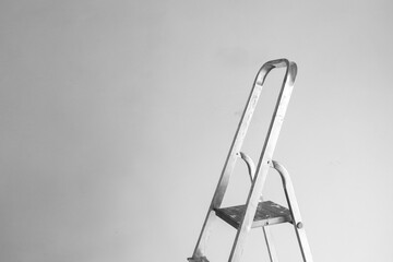 Metal ladder positioned against a plain gray wall in a minimal workspace