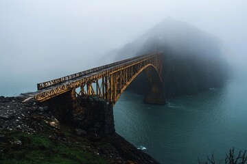 Obraz premium Misty wooden bridge leads to a lonely tree on a rocky island during early morning fog