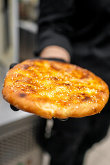 A freshly baked, golden-brown flatbread topped with melted cheese and sesame seeds. The warm, inviting texture showcases a perfect crust, ready to be enjoyed.