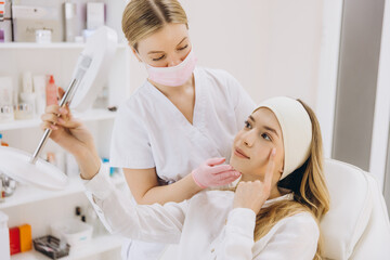 Doctor showing botox injection results to a patient with a mirror in a medical spa center